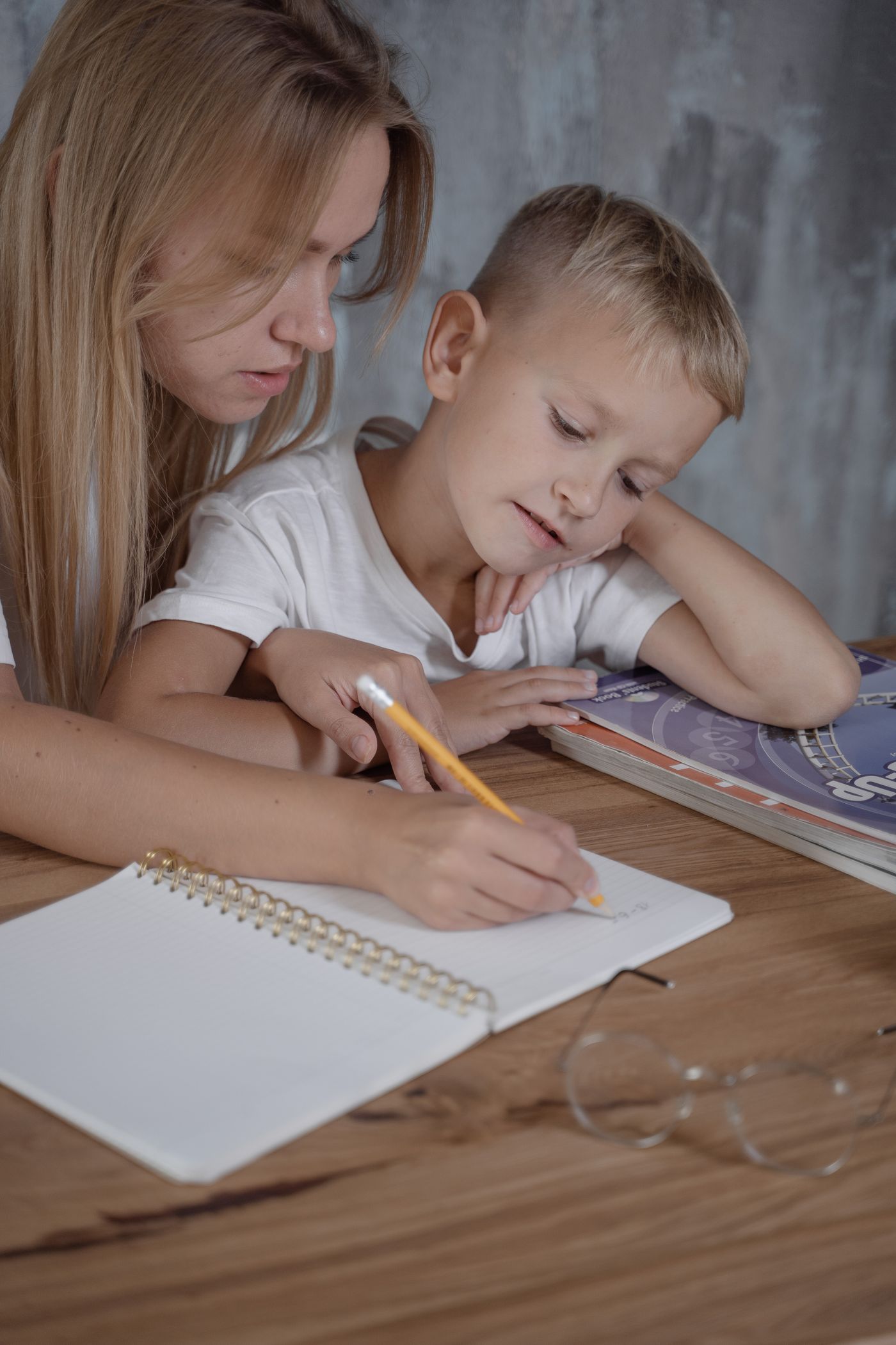 A parent helping a child with homework at the table
